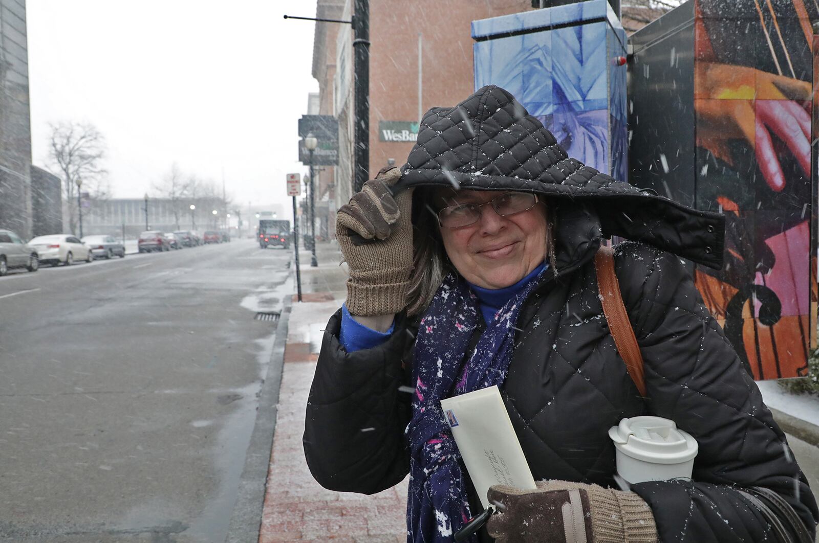 Eileen Johnson uses the hood to shield her face from the blowing snow Wednesday as she crosses Main Street in Springfield as it begins to snow. BILL LACKEY/STAFF