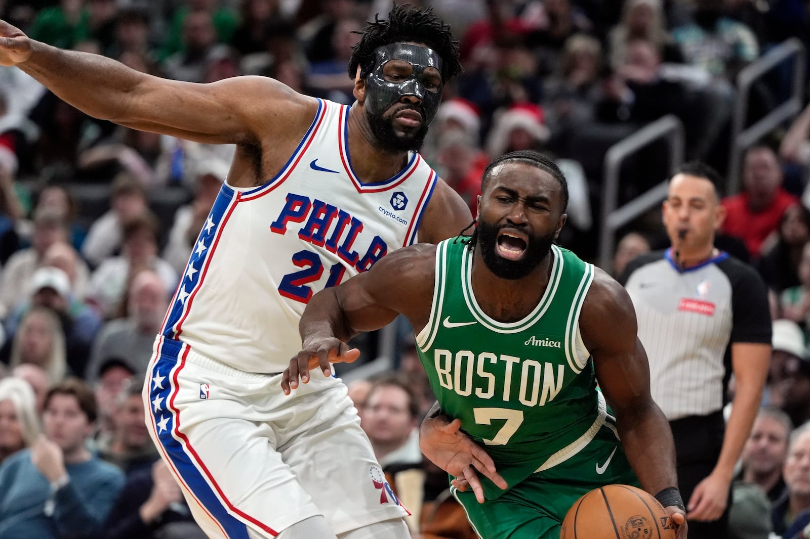 Boston Celtics' Jaylen Brown (7) drives past Philadelphia 76ers' Joel Embiid (21) during the first half of an NBA basketball game, Wednesday, Dec. 25, 2024, in Boston (AP Photo/Michael Dwyer)