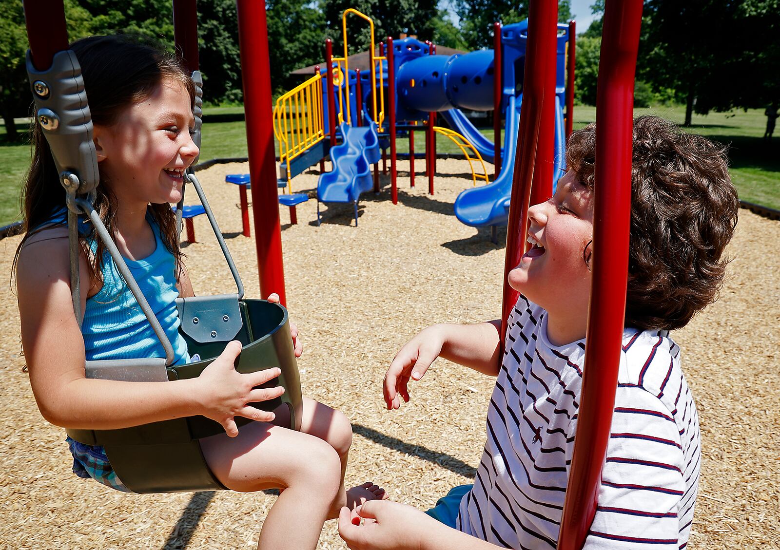 Arrionna Massie laughes with her big brother Aiden as the two ride a tandem swing on the new playground at New Reid Park Thursday. BILL LACKEY/STAFF