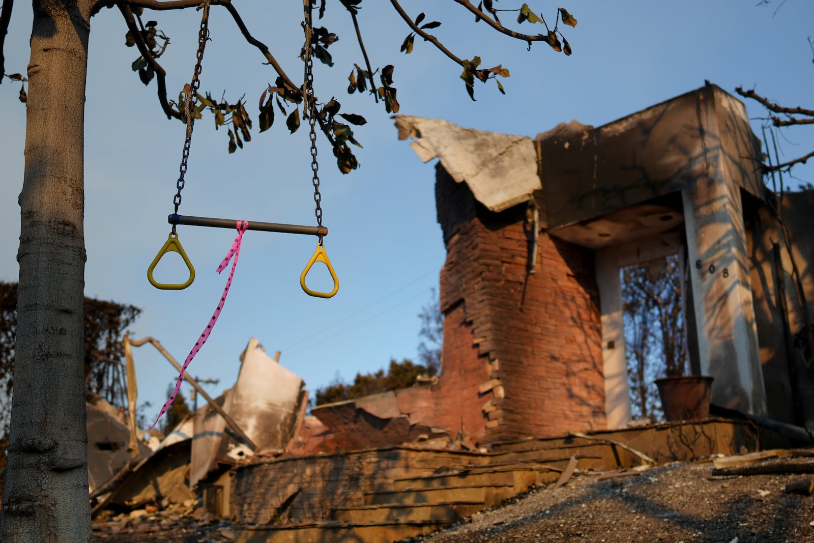 A swing hangs from a tree in front of a fire-damaged residence in the aftermath of the Palisades Fire in the Pacific Palisades neighborhood of Los Angeles, Friday, Jan. 10, 2025. (AP Photo/Eric Thayer)