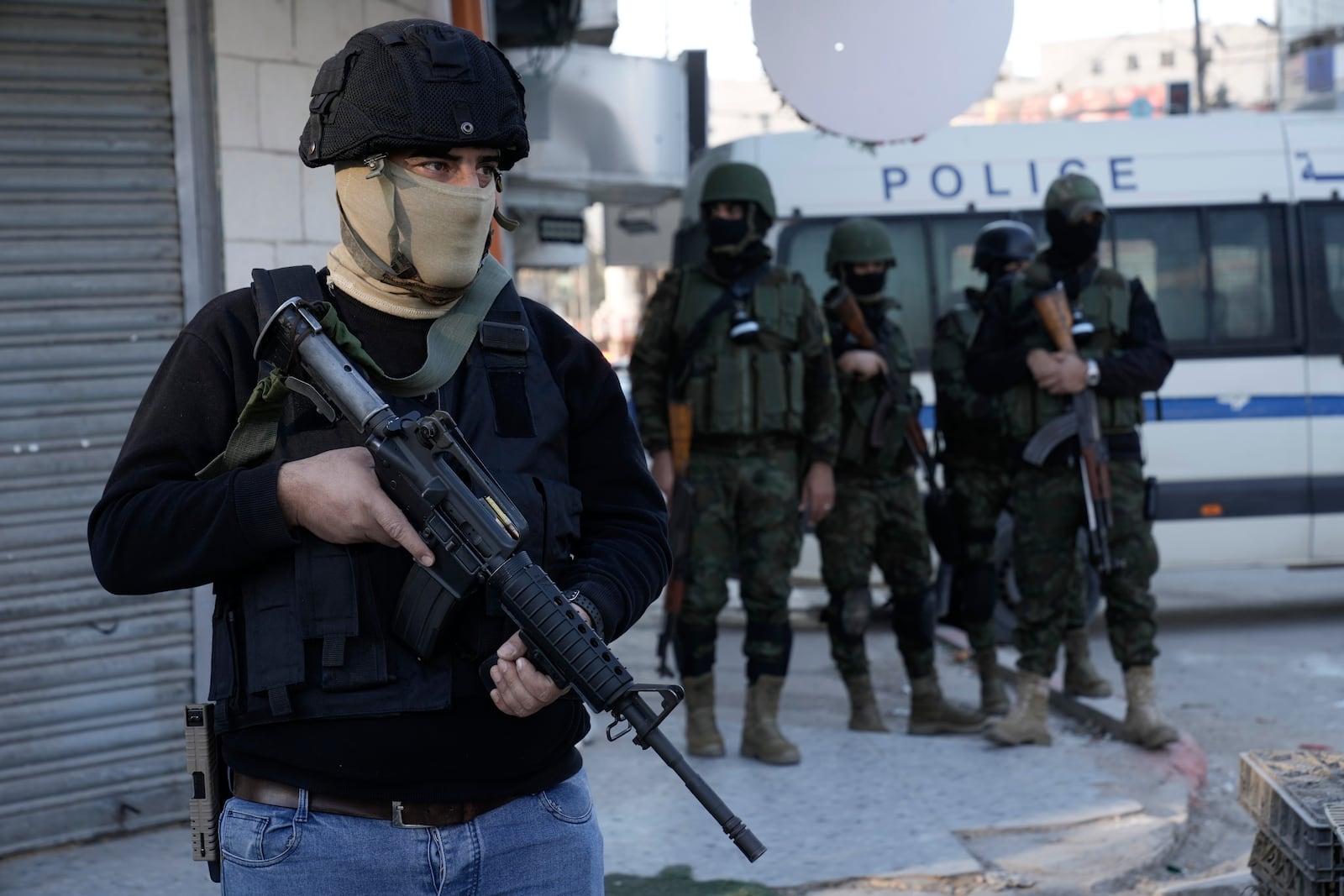 A officer from the Palestinian Authority clutches his gun as Palestinian security forces mount a major raid against militants in the Jenin refugee camp in the Israeli-occupied West Bank, Monday, Dec. 16, 2024.(AP Photo/Majdi Mohammed).