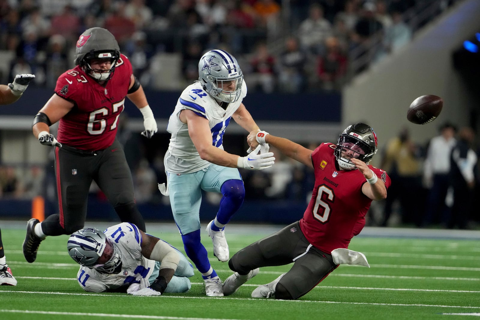 Dallas Cowboys linebacker Micah Parsons (11) strips the ball away from Tampa Bay Buccaneers quarterback Baker Mayfield (6) as Nick Vigil (41) attempts to recover the ball that fell out-of-bounds in the second half of an NFL football game in Arlington, Texas, Sunday, Dec. 22, 2024. (AP Photo/Jeffrey McWhorter)