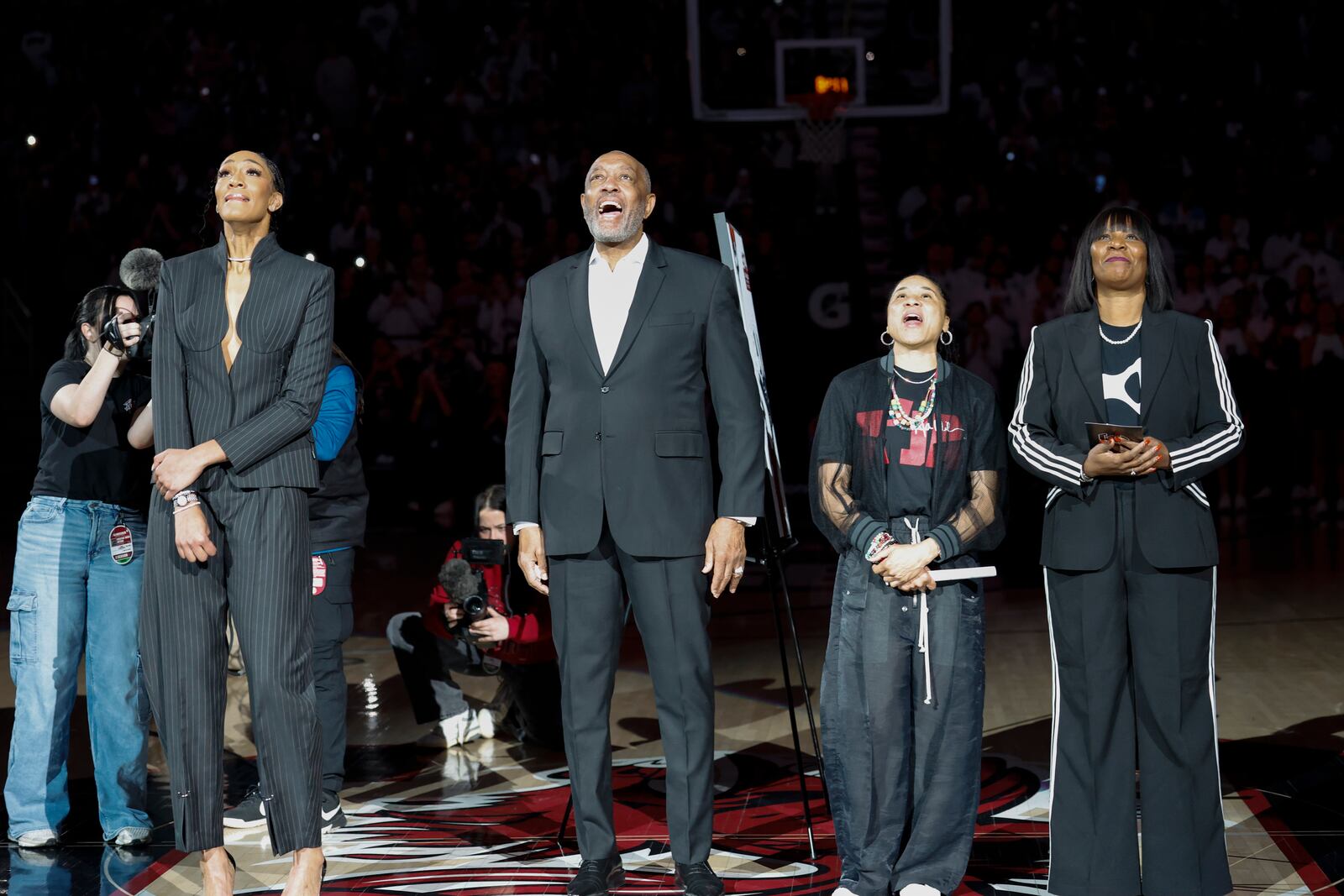 A'ja Wilson, center, stands with her parents Eva and Roscoe Wilson as they watch her number be retired during a ceremony before an NCAA college basketball game between South Carolina and Auburn in Columbia, S.C., Sunday, Feb. 2, 2025. (AP Photo/Nell Redmond)