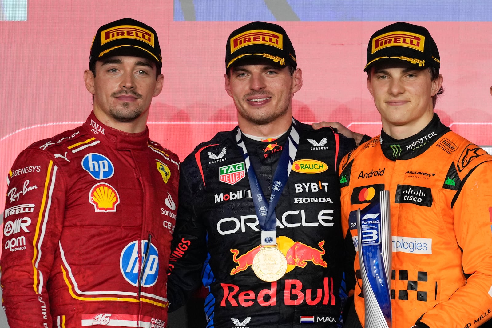 From the left, second-aced Ferrari driver Charles Leclerc of Monaco, first-placed Red Bull driver Max Verstappen of the Netherlands, and third-placed McLaren driver Oscar Piastri of Australia stand on the podium during the Qatar Formula One Grand Prix at the Lusail International Circuit in Lusail, Qatar, Sunday, Dec. 1, 2024. (AP Photo/Altaf Qadri)