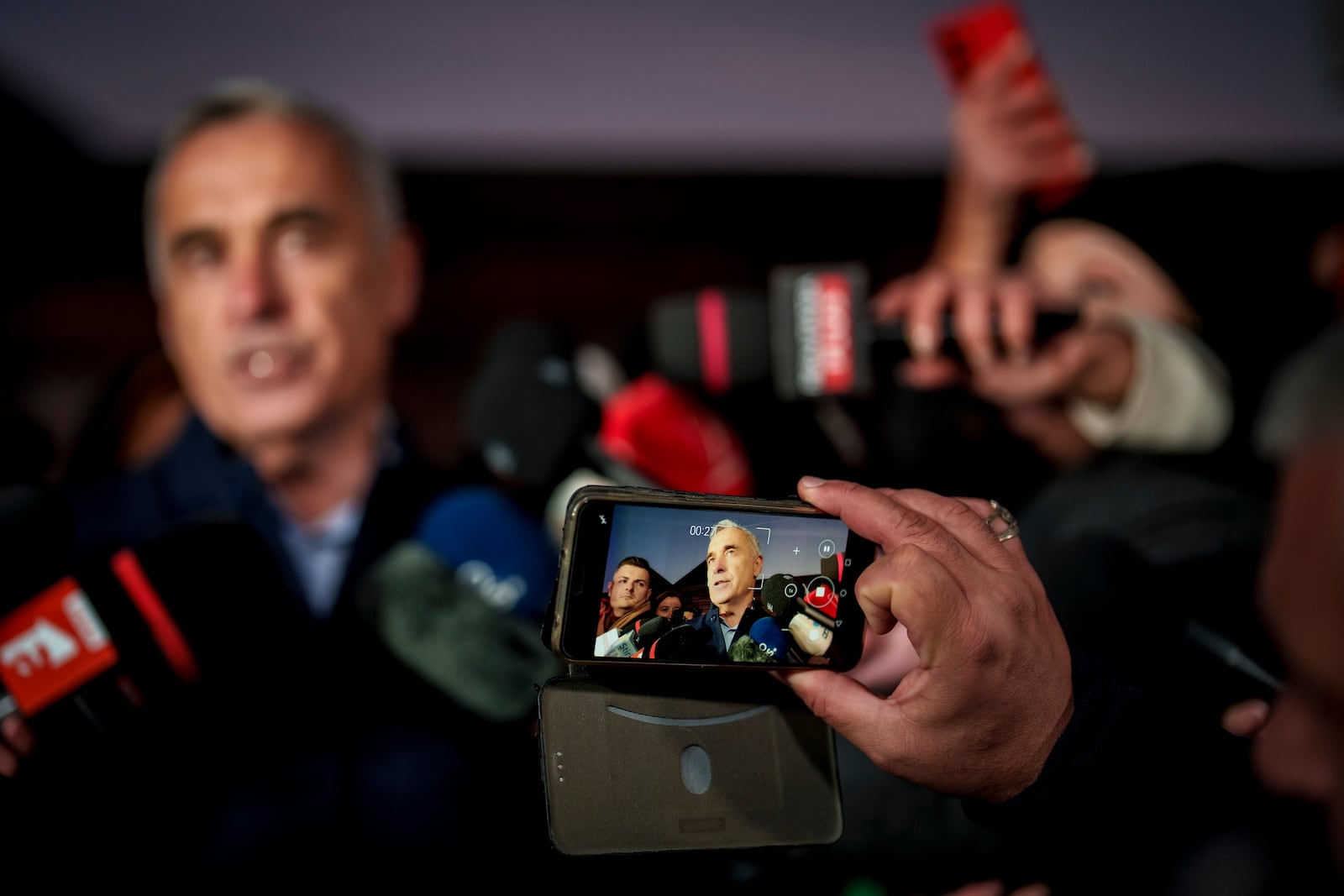 A journalist records Calin Georgescu, running as an independent candidate for president gestures while delivering a speech to media, in Izvorani, Romania, Tuesday, Nov. 26, 2024, after making it to the Dec. 8 election runoff. (AP Photo/Vadim Ghirda)