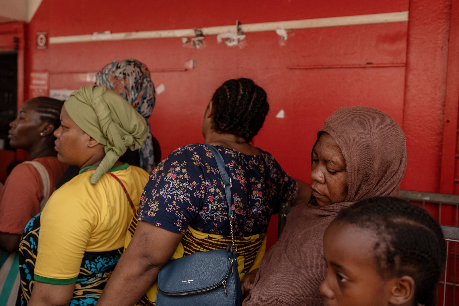 Women wait for supplies to be delivered at a supermarket in Mamoudzou, Mayotte, Friday, Dec. 20, 2024. (AP Photo/Adrienne Surprenant)