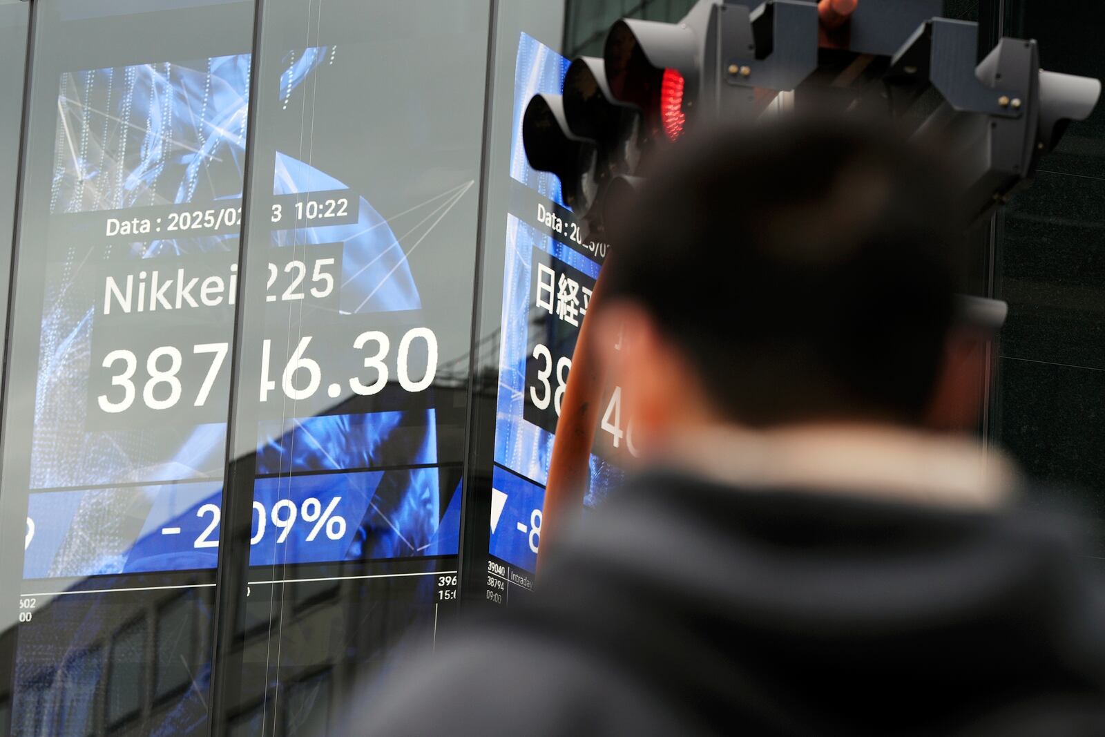 A person walks in front of an electronic stock board showing Japan's Nikkei index at a securities firm Monday, Feb. 3, 2025, in Tokyo. (AP Photo/Eugene Hoshiko)