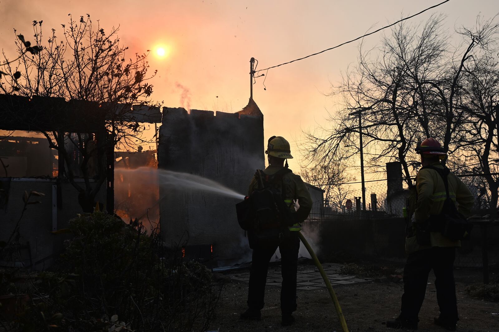 Firefighters water down a home after the Eaton Fire burns in Altadena, Calif., Thursday, Jan. 9, 2025. (AP Photo/Nic Coury)