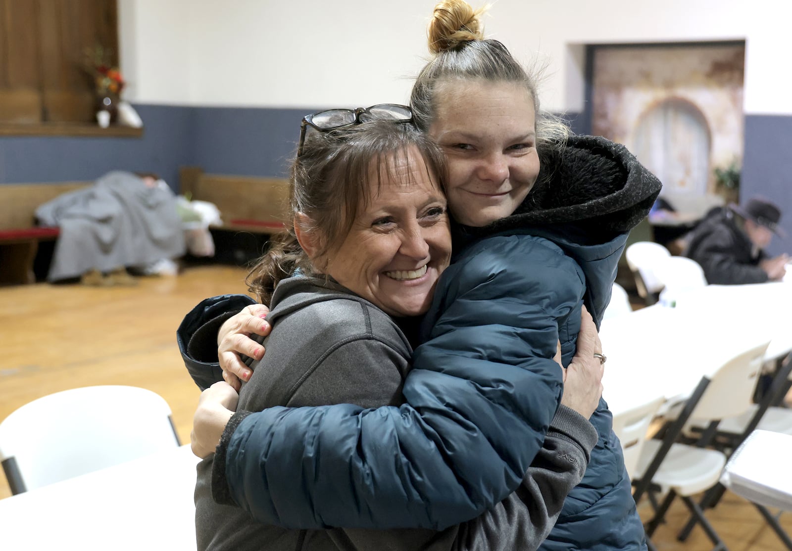 Jazmine Truesdale, who is homeless, hugs Springfield Warming Center volunteer, Jodie Brann, Wednesday, Jan. 8, 2025 at the warming center. As temperatures dropped below freezing, the number of homeless people using the center has increased. BILL LACKEY/STAFF