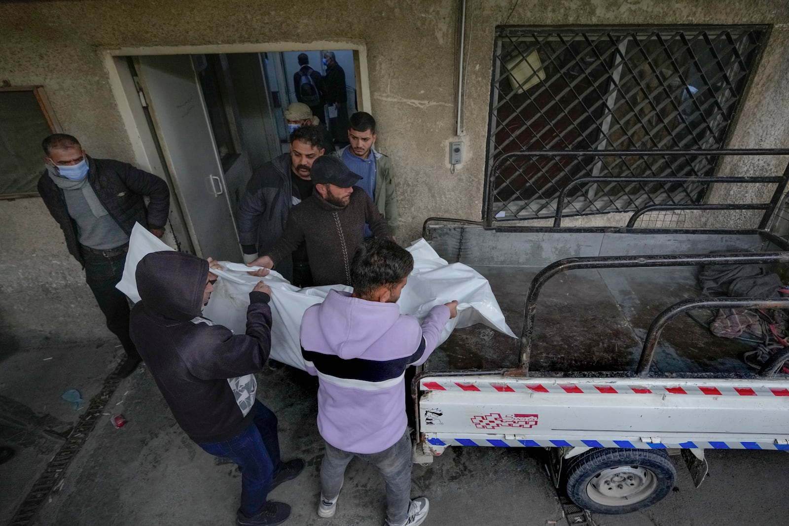 Syrian citizens carry the body of Sami Chouaib, 34, who had been a prisoner of Syrian security forces, after his body was found at the Al-Mojtahed Hospital morgue in Damascus, Syria, on Wednesday, Dec. 11, 2024. Many people are flocking to morgues, hoping to identify loved ones who were either killed or imprisoned under President Bashar Assad's government, which collapsed over the weekend. (AP Photo/Hussein Malla)