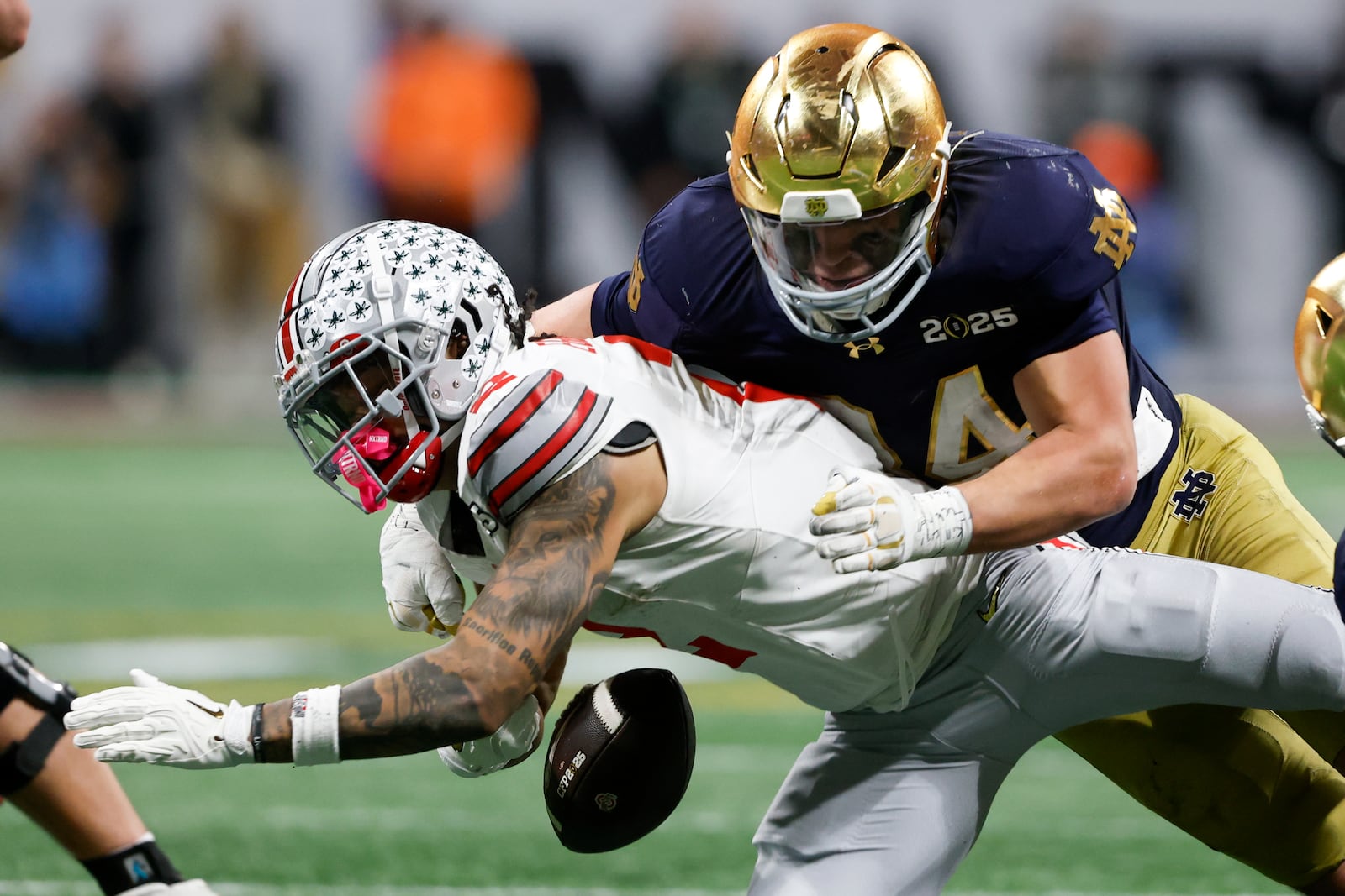 Notre Dame linebacker Drayk Bowen forces a fumble by Ohio State wide receiver Emeka Egbuka during second half of the College Football Playoff national championship game Monday, Jan. 20, 2025, in Atlanta. (AP Photo/Butch Dill)