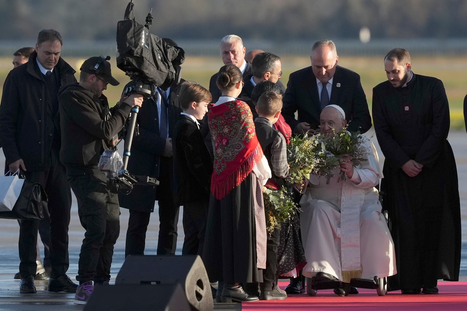 Pope Francis is welcomed by children as he arrives at Ajaccio International Airport on the occasion of his one-day visit in the French island of Corsica, Sunday, Dec. 15, 2024. (AP Photo/Alessandra Tarantino)