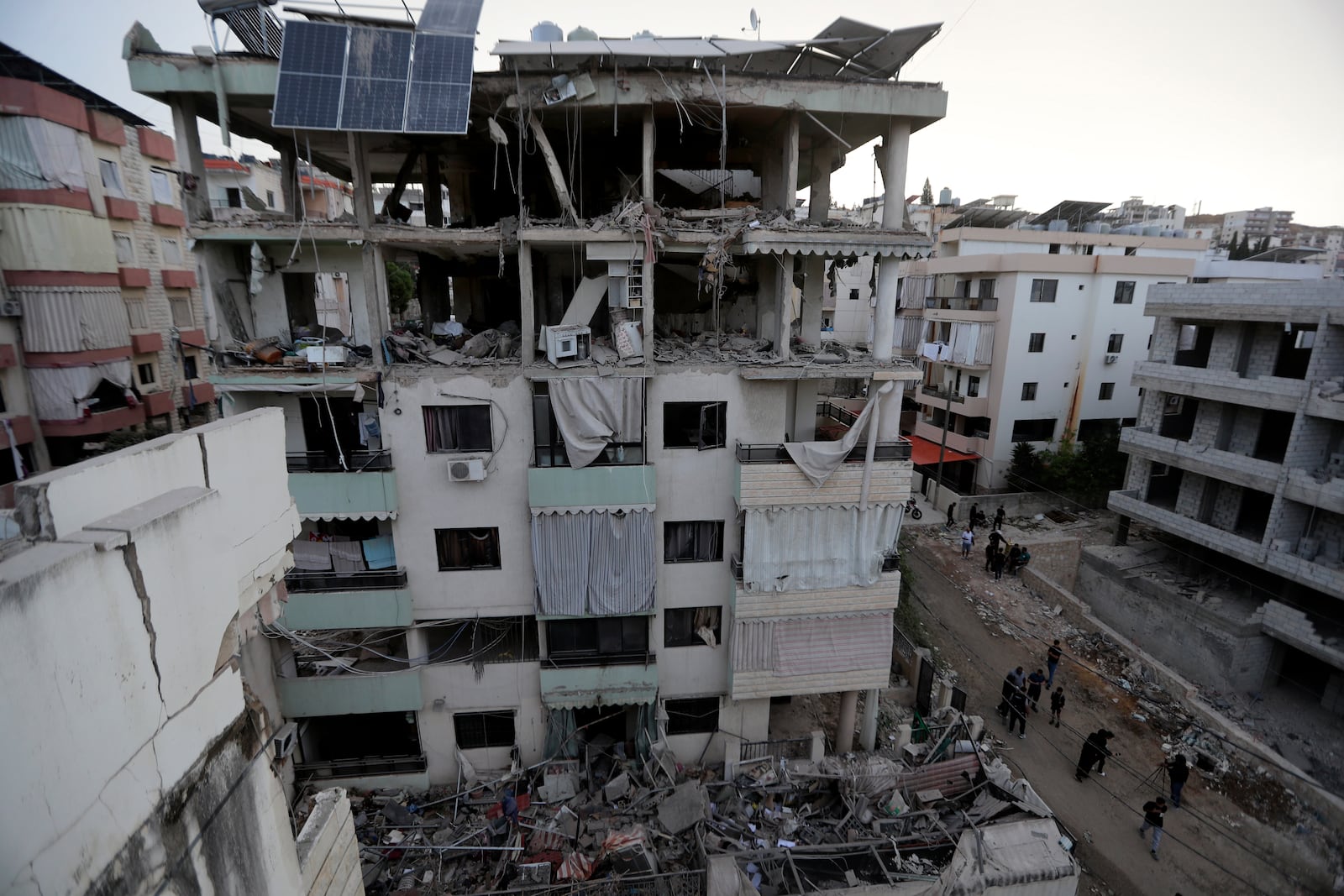 People walk past a destroyed building hit in an Israeli airstrike, in the southern port city of Sidon, Lebanon, Sunday, Nov. 3, 2024. (AP Photo/Mohammed Zaatari)