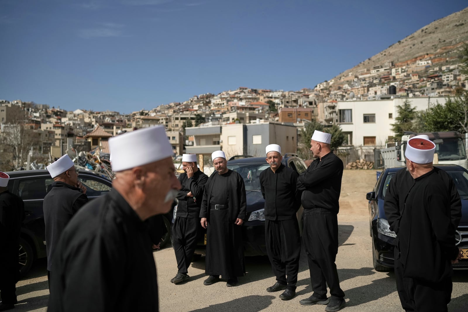 Druze clerics stand near the border, as they wait for buses carrying members of the Syrian Druze community to cross from Syria in the village of Majdal Shams, in the Israeli-controlled Golan Heights, Friday, March 14, 2025. (AP Photo/Leo Correa)