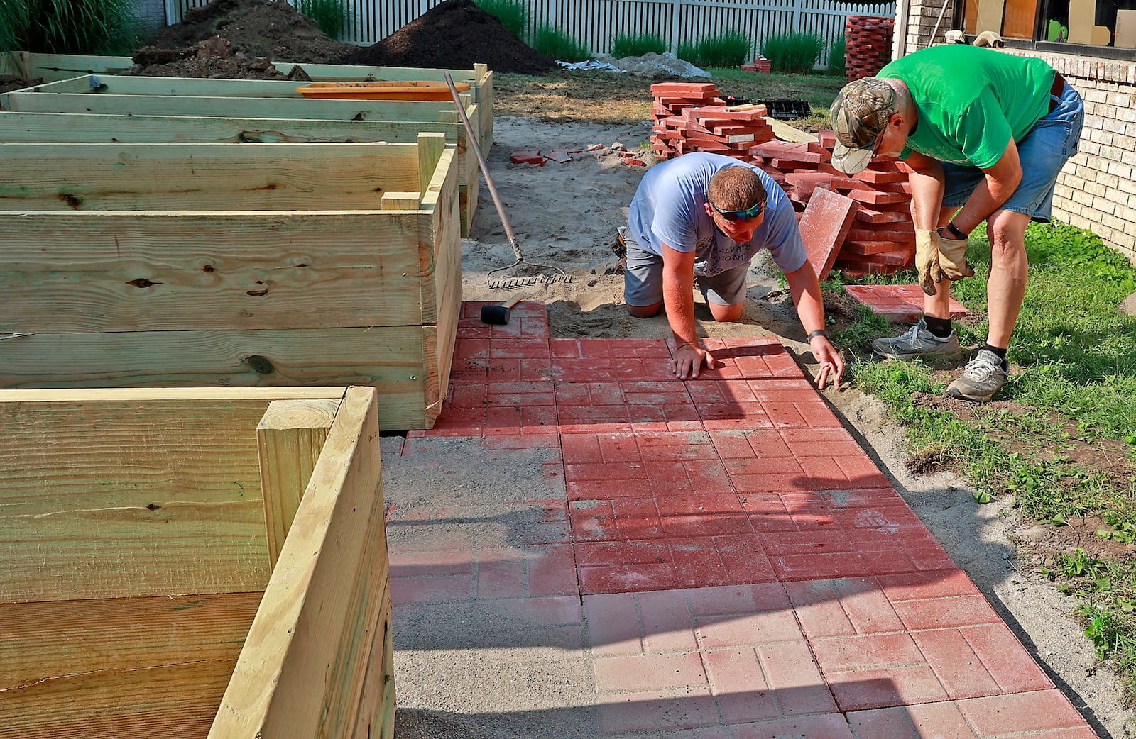 Members of the Clark County Senior Citizens Task Force work on a new handicapped accessible raised garden with paved walkways in the courtyard of the Good Shepherd Village Nursing Center. Alex Flora, left, and Larry Richards placing pavers around the garden Wednesday, July 12, 2023 that will allow the residents to grow flowers and vegetables. BILL LACKEY/STAFF