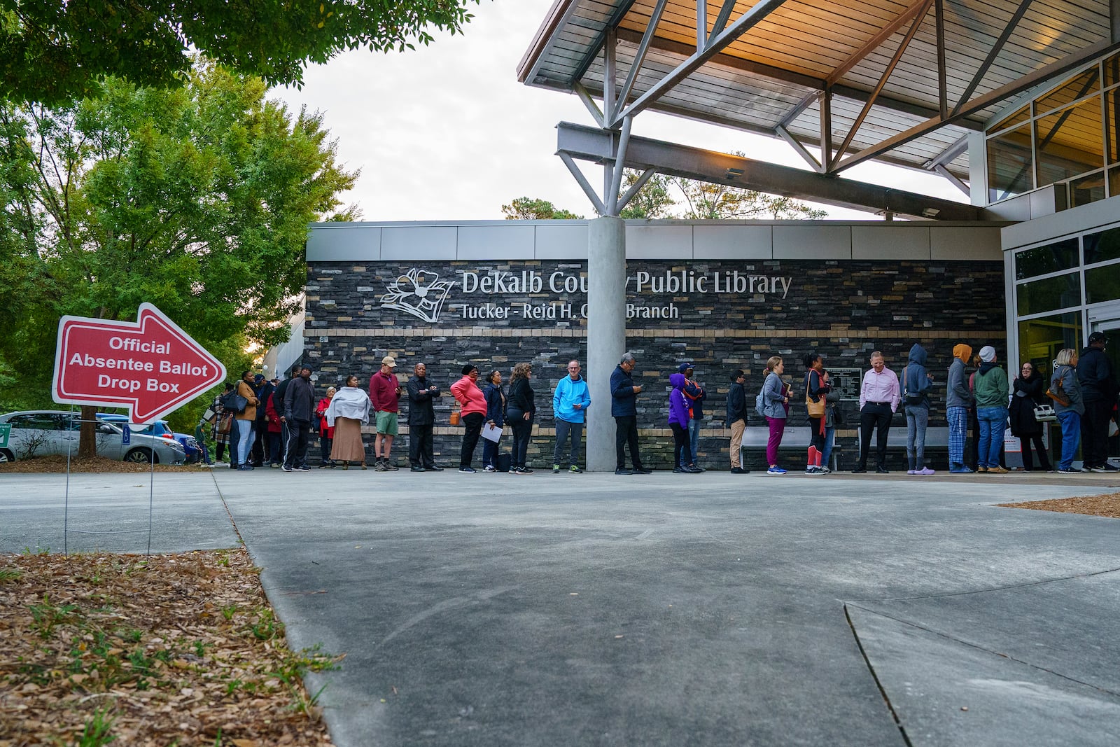 People line up around the building at the Tucker-Reid H. Cofer branch of the Dekalb County Public Library on the first day of early voting, Tuesday, Oct. 15, 2024 in Tucker, Ga. (Matthew Pearson/WABE via AP)