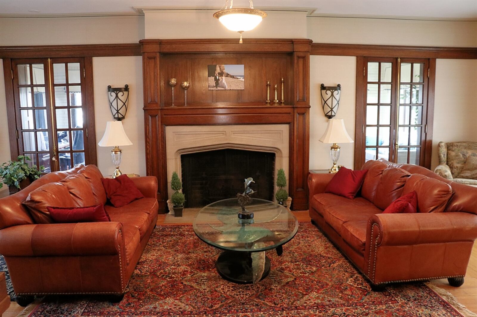 The spacious living room has a fireplace with limestone surround and hearth with crafted wood mantel. Two sets of French doors open into a sunroom that has a wall of built-ins to allow for flexible floor-plan options. 