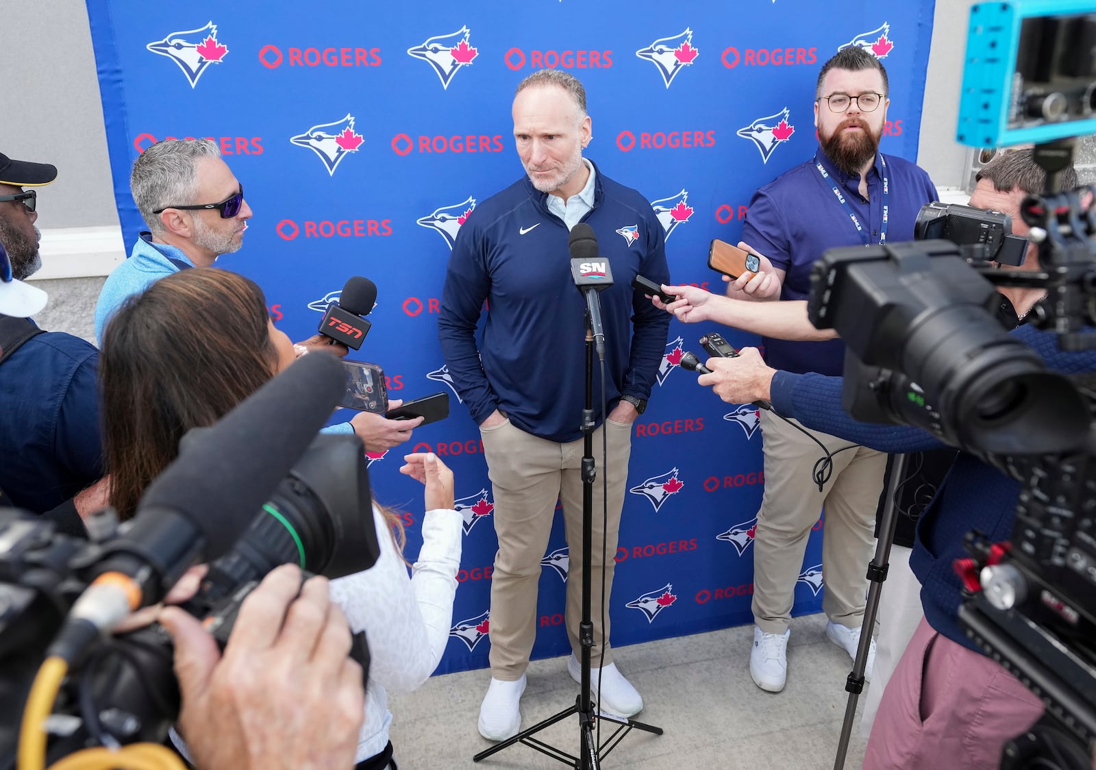 Mark Shapiro, center, president and CEO of the Toronto Blue Jays, speaks to the media about first baseman Vladimir Guerrero Jr. during spring training baseball workouts in Dunedin Fla., Tuesday, Feb. 18, 2025. (Nathan Denette/The Canadian Press via AP)