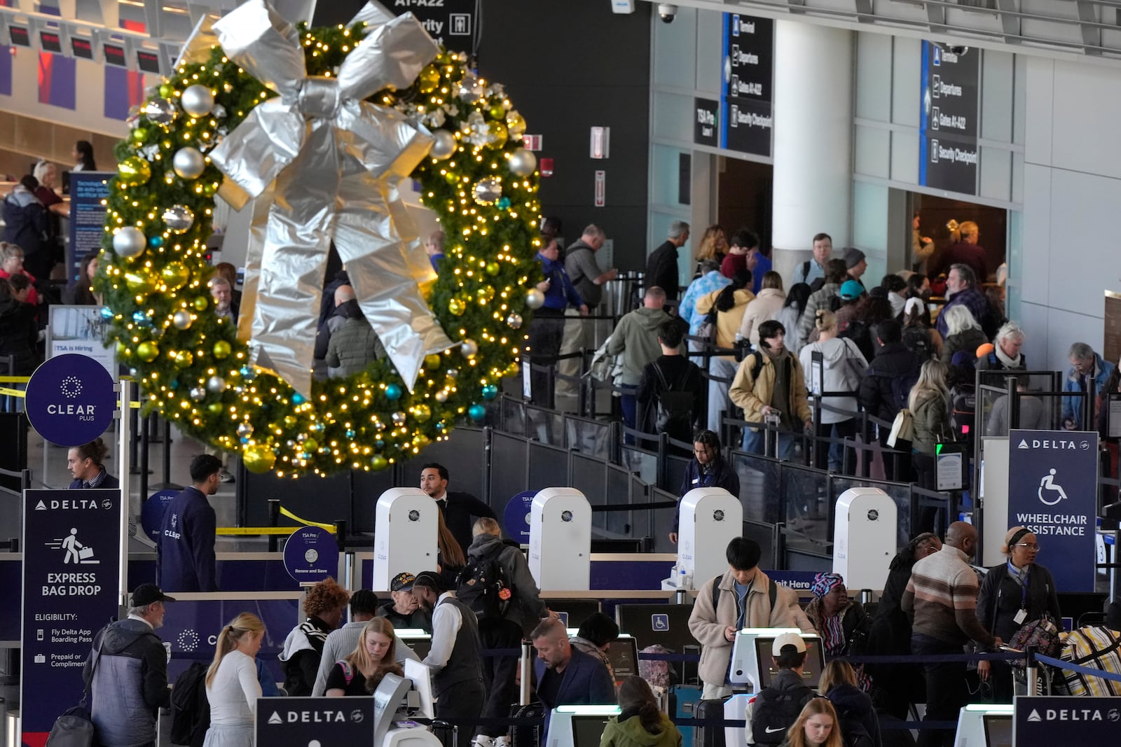 Travelers prepare to board aircraft near a holiday decoration, top, Monday, Nov. 25, 2024, at Boston Logan International Airport, in Boston. (AP Photo/Steven Senne)