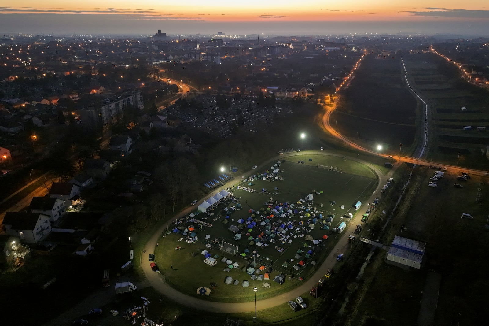 An aerial view of students sleeping in their tents on a soccer stadium as they take part in a march and protest over the collapse of a concrete canopy that killed 15 people more than two months ago, in Indjija, Serbia, Friday, Jan. 31, 2025. (AP Photo/Armin Durgut)