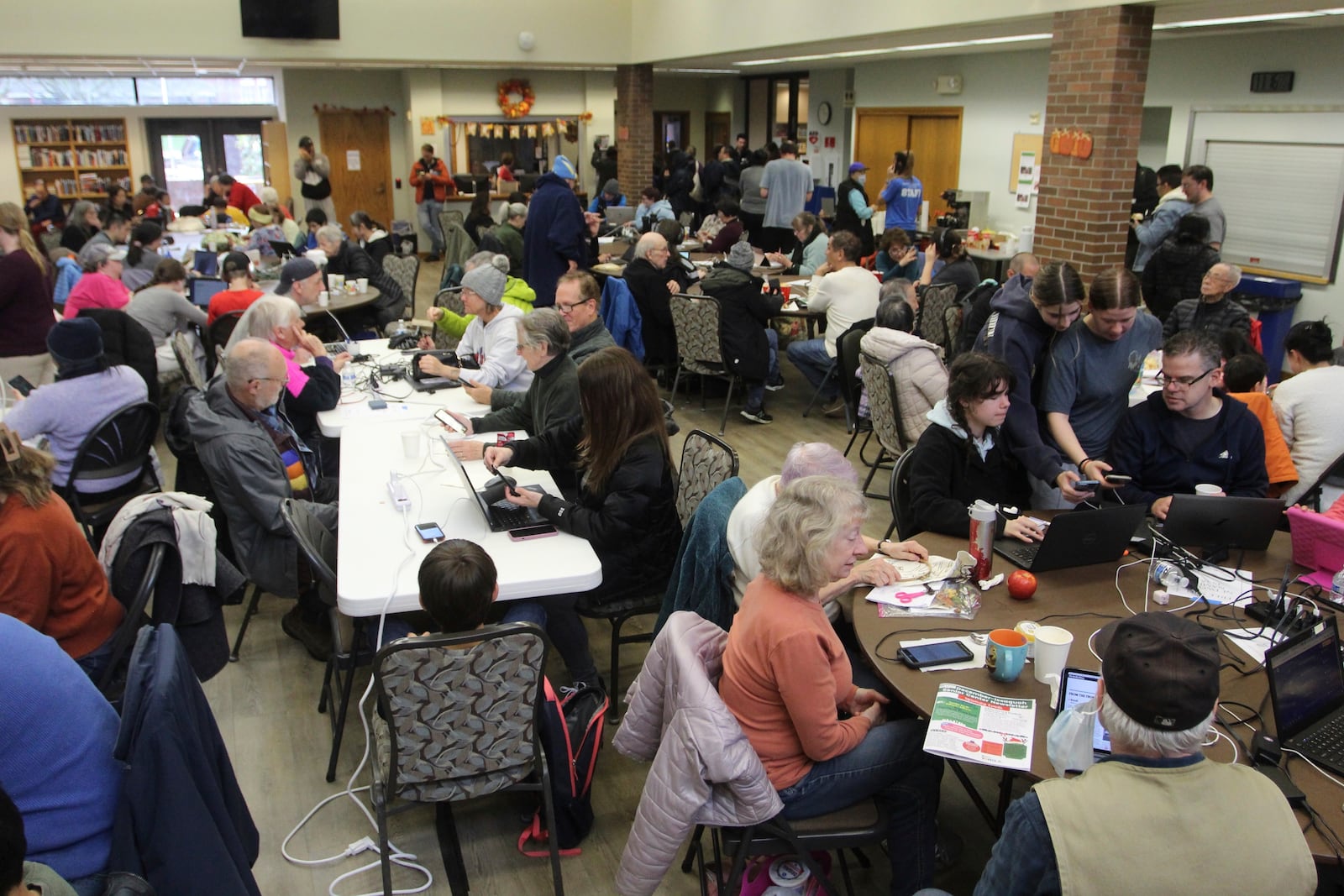 People gather to charge their electronic devices, keep warm and eat snacks at a senior center in Issaquah, Wash., Friday, Nov. 22, 2024, after a high winds from a storm knocked out power. (AP Photo/Manuel Valdes)