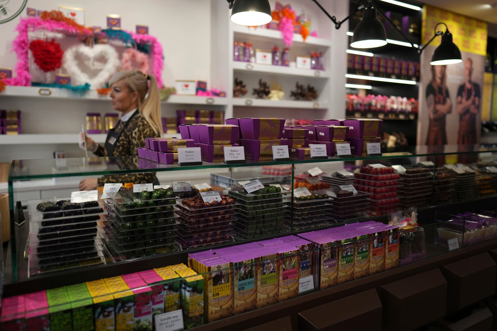 A saleswoman walks by boxes of artisan chocolates at The Chocolate Line in Bruges, Belgium, Thursday, Feb. 6, 2025. (AP Photo/Virginia Mayo)