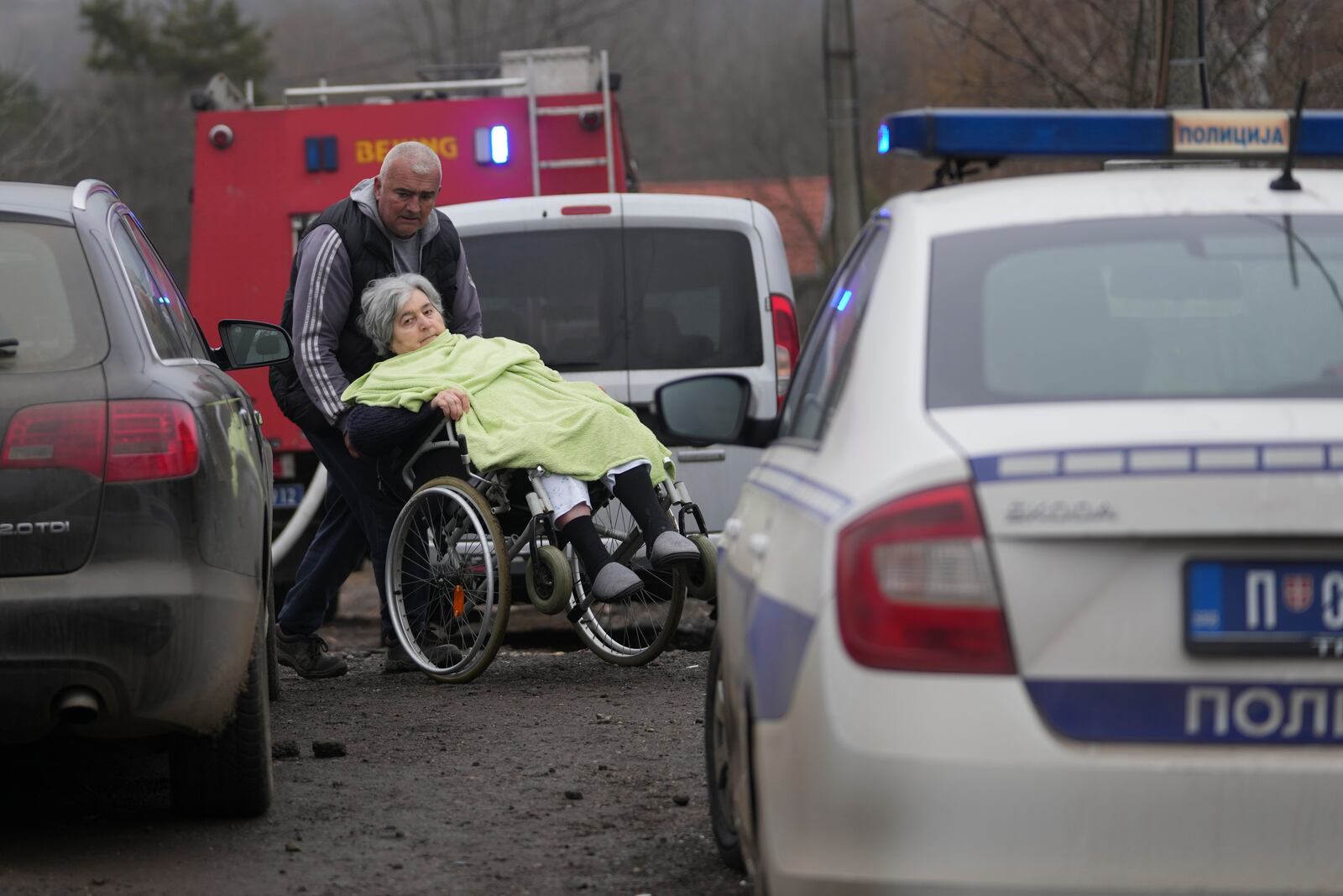 People evacuate people in front of a home for the elderly where eight people died in a fire, in Barajevo, a municipality of Belgrade, Serbia, Monday, Jan. 20, 2025. (AP Photo/Darko Vojinovic)