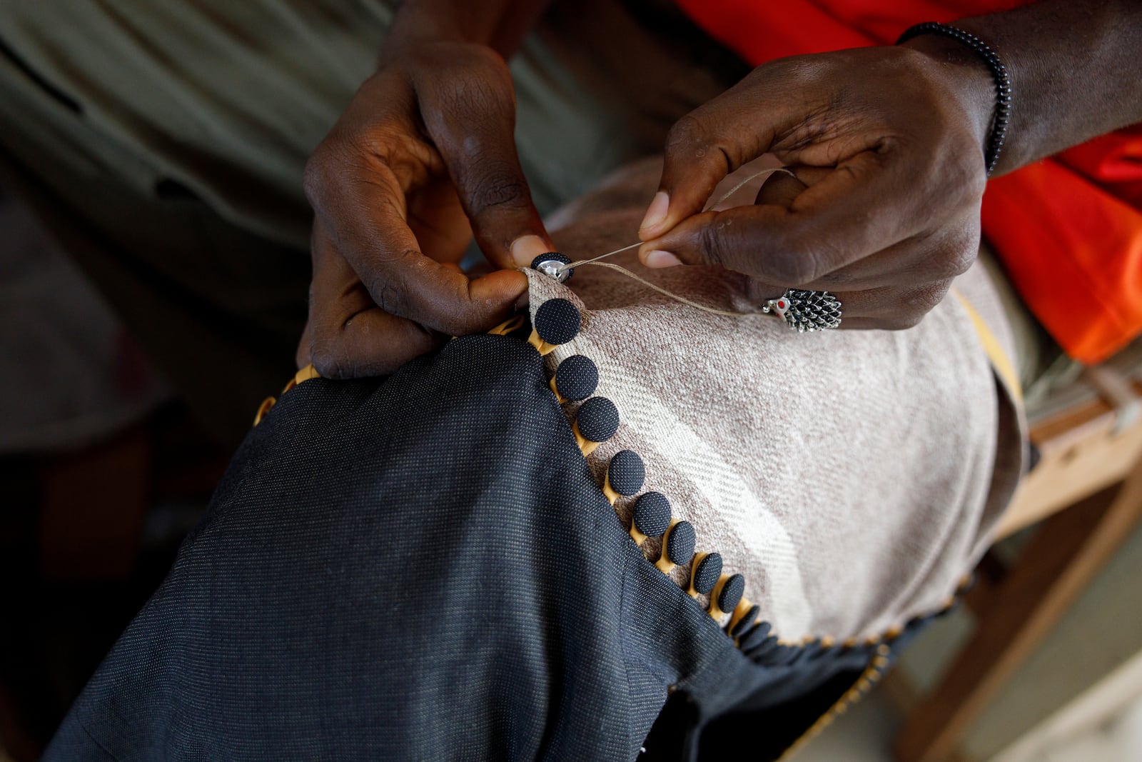 An upcycle designer stitches buttons on an upcycled cloth in the remanufacturing space at the OR Foundation in Accra, Ghana, Thursday, Oct. 24, 2024. (AP Photo/Misper Apawu)