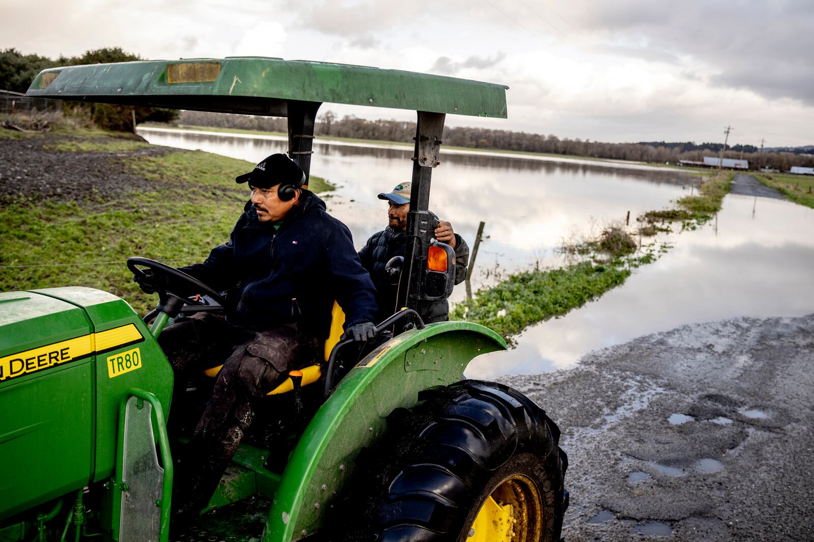 Jorge Martinez, left, and Manuel Barral pause after the crossed a road flooded by rain waters from the nearby Eel River in Ferndale, Calif., Friday, Nov. 22, 2024.(Stephen Lam/San Francisco Chronicle via AP)