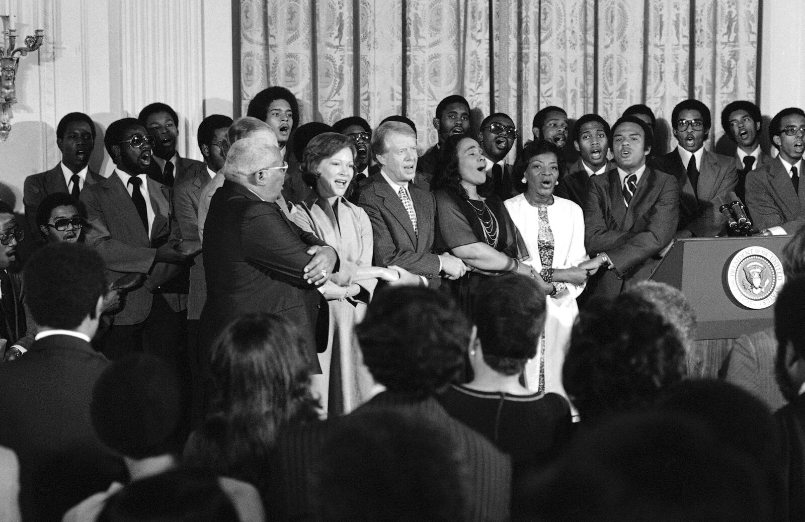 FILE - Dr. Martin Luther King Sr., Rosalynn Carter, President Jimmy Carter, Coretta Scott King, Christine Parris King, sister of the late Dr. King, and U.N. Ambassador Andrew Young sing during a reception honoring friends of the Martin Luther King Jr. Center for Social Change in Washington on Oct. 3, 1978. (AP Photo/Barry Thumma, File)