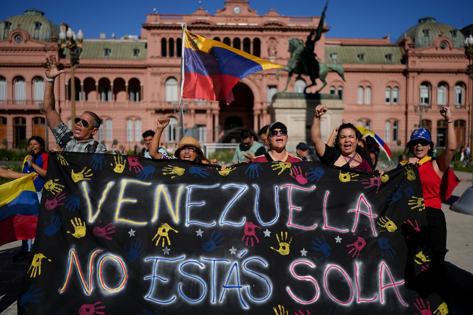 Opponents of Venezuelan President Nicolas Maduro hold a banner that reads in Spanish: "Venezuela, you're not alone" at Plaza de Mayo in Buenos Aires, Argentina, Thursday, Jan. 9, 2025, the day before Maduro's inauguration for a third term. (AP Photo/Natacha Pisarenko)