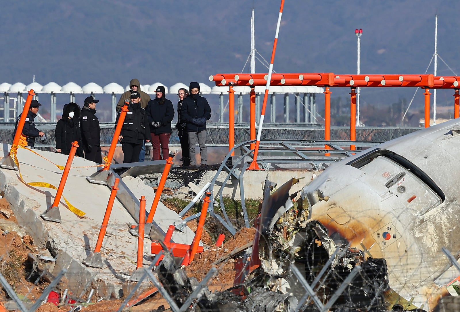 Experts from the U.S. National Transportation Safety Board (NTSB) and joint investigation team between the U.S. and South Korea check the site of a plane crash at Muan International Airport in Muan, South Korea, Tuesday, Dec. 31, 2024. (Son Hyung-joo/Yonhap via AP)