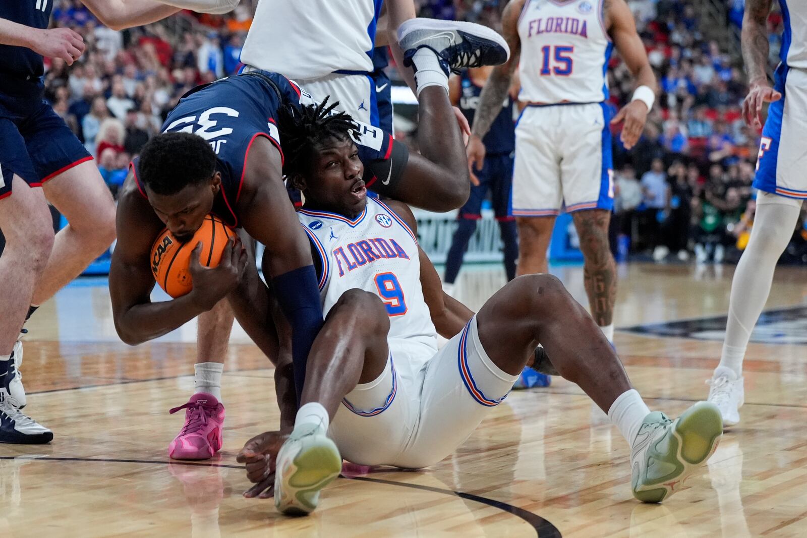 UConn center Samson Johnson falls over Florida center Rueben Chinyelu during the first half in the second round of the NCAA college basketball tournament, Sunday, March 23, 2025, in Raleigh, N.C. (AP Photo/Chris Carlson)