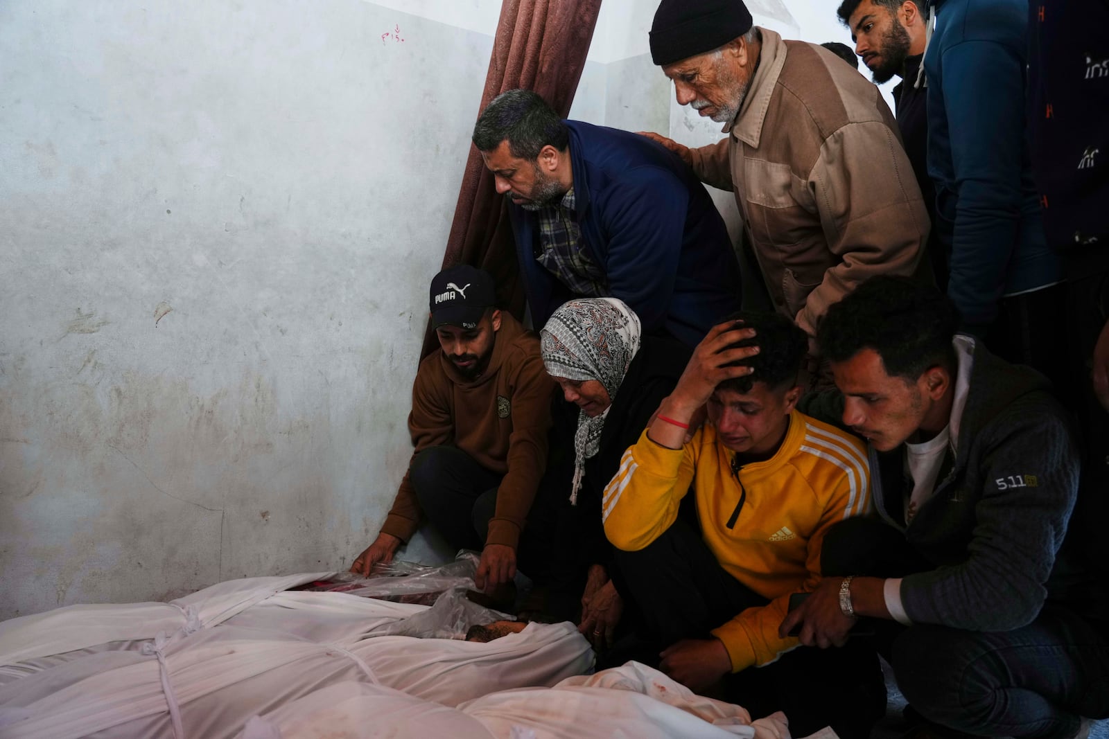 Palestinians mourn over the bodies of their relatives killed by an Israeli airstrike in the Netzarim corridor, at the Al-Ahli Hospital in Gaza City on Tuesday, March 11, 2025. (AP Photo/(AP Photo/Jehad Alshrafi)