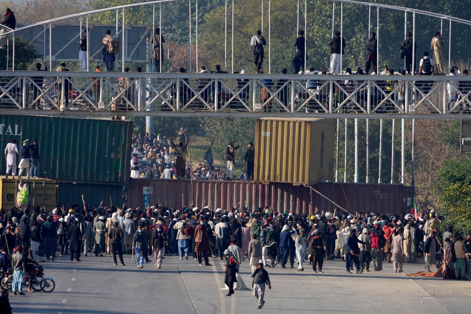 Supporters of imprisoned former premier Imran Khan's Pakistan Tehreek-e-Insaf party, gather to remove shipping container to clear way for their rally demanding Khan's release, in Islamabad, Pakistan, Tuesday, Nov. 26, 2024. (AP Photo/Anjum Naveed)