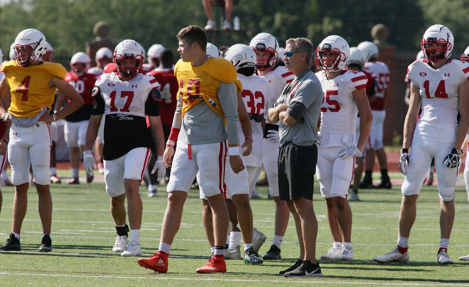 Wittenberg coach Jim Collins, right center, and quarterback Collin Brown (No. 10), watch practice on Thursday, Aug. 18, 2022, at Edwards-Maurer Field in Springfield. David Jablonski/Staff