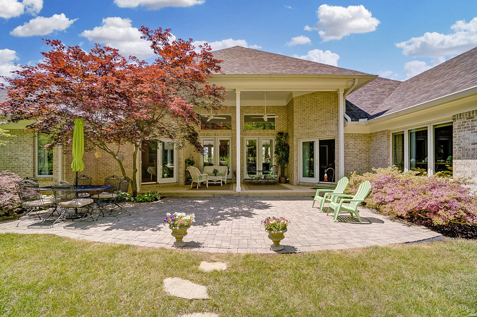 The rear of the home features a covered rear concrete patio with double ceiling fans. The patio steps down to a paver patio extension, surrounded by landscaping and leading the back lawn. CONTRIBUTED PHOTO