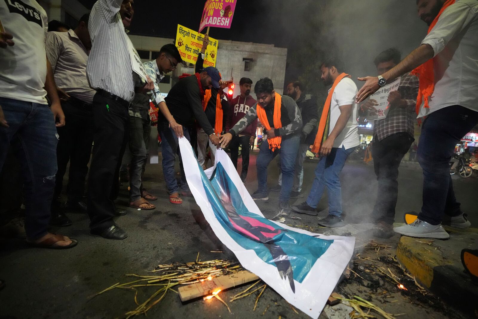 Activists of Bajarang dal, a Hindu rights group, burn an effigy of Bangladesh's interim leader Muhammad Yunus and a symbolic flag of Bangladesh, during a protest against the alleged attacks on Hindus in Bangladesh, in Ahmedabad, India, Wednesday, Dec. 11, 2024. (AP Photo/Ajit Solanki)