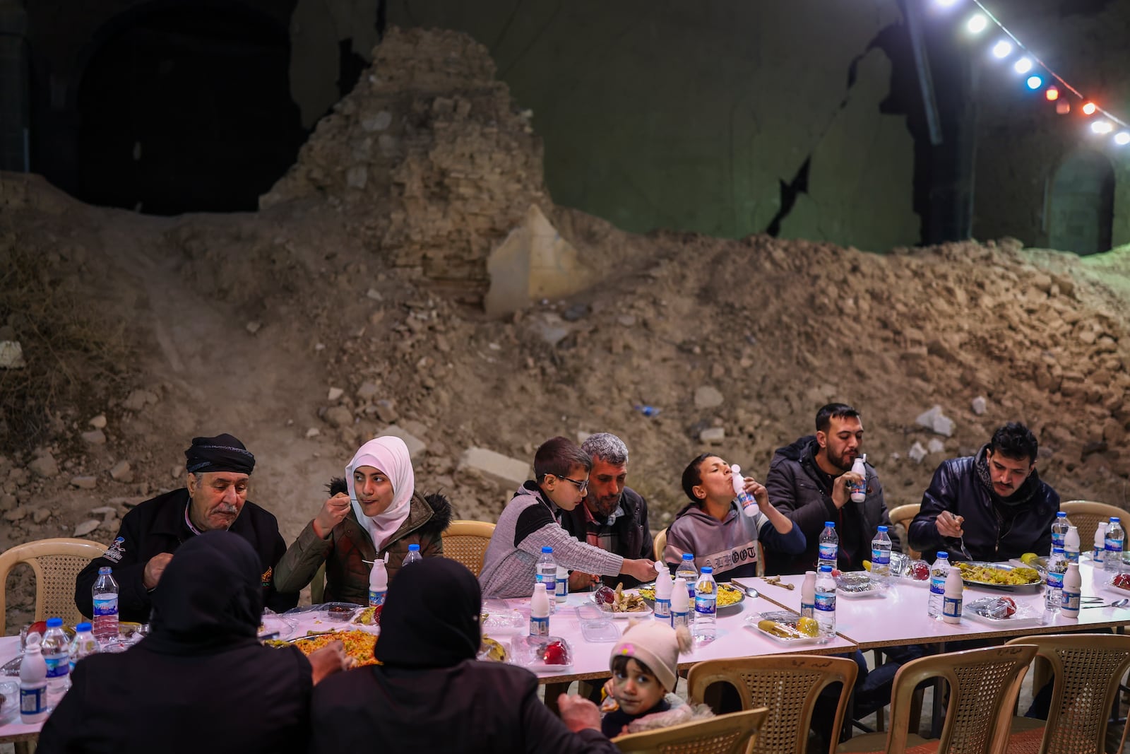 Residents gather for iftar, the fast-breaking meal, organized by the Turkish Humanitarian Relief Foundation (IHH), on the first day of Ramadan in the Jobar neighborhood, which was devastated by the Syrian war, in Damascus, Syria, on Saturday, March 1, 2025.(AP Photo/Ghaith Alsayed)