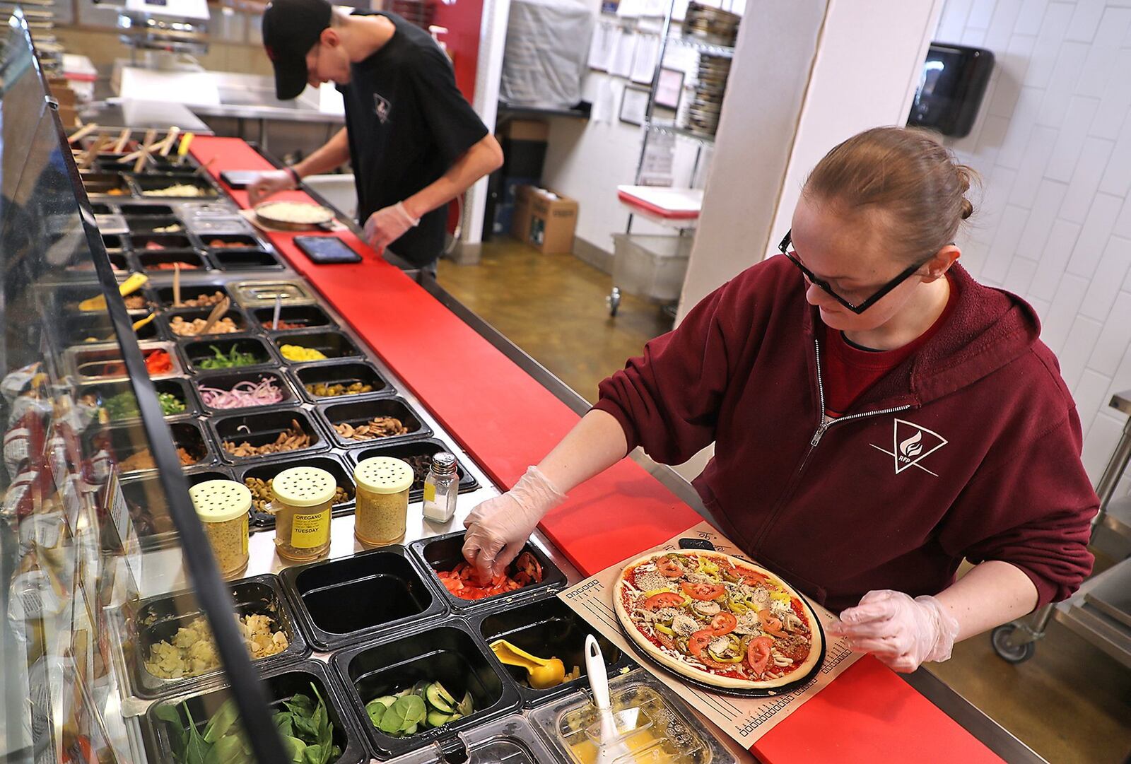 Rita McClure prepares a customer’s order at Rapid Fired Pizza in Springfield. BILL LACKEY/STAFF