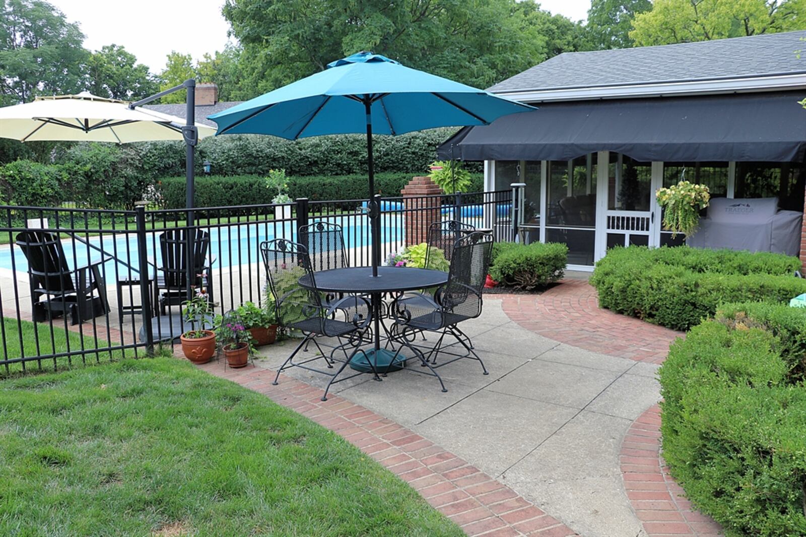 Outside the pool area is a paver-brick patio, surrounded by garden beds, which has access to a screen-enclosed patio with a cathedral ceiling and outside awnings.