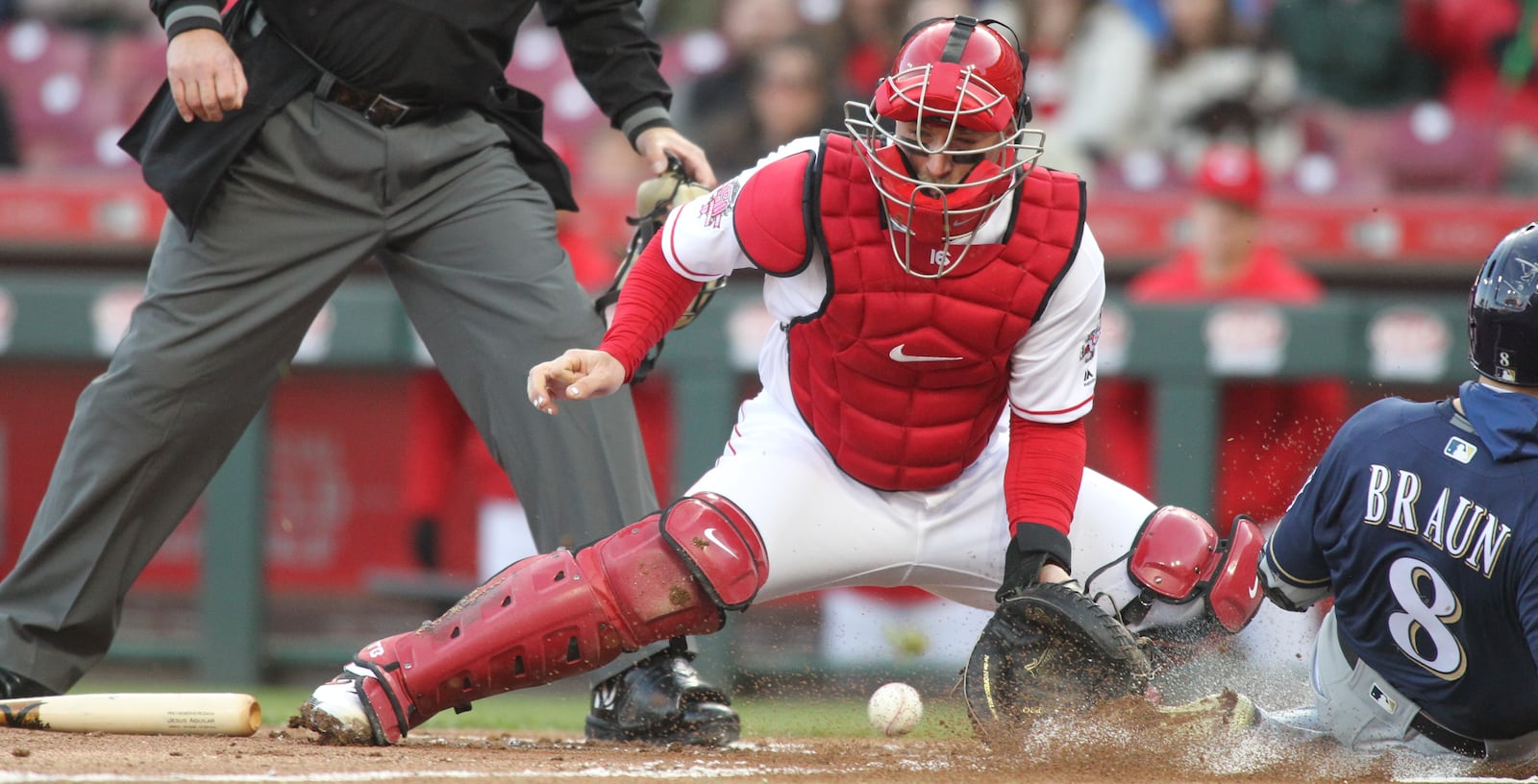 Reds catcher Tucker Barnhart fields a throw as Ryan Braun scores for the Brewers in the first inning on Monday, April 1, 2019, at Great American Ball Park in Cincinnati. David Jablonski/Staff