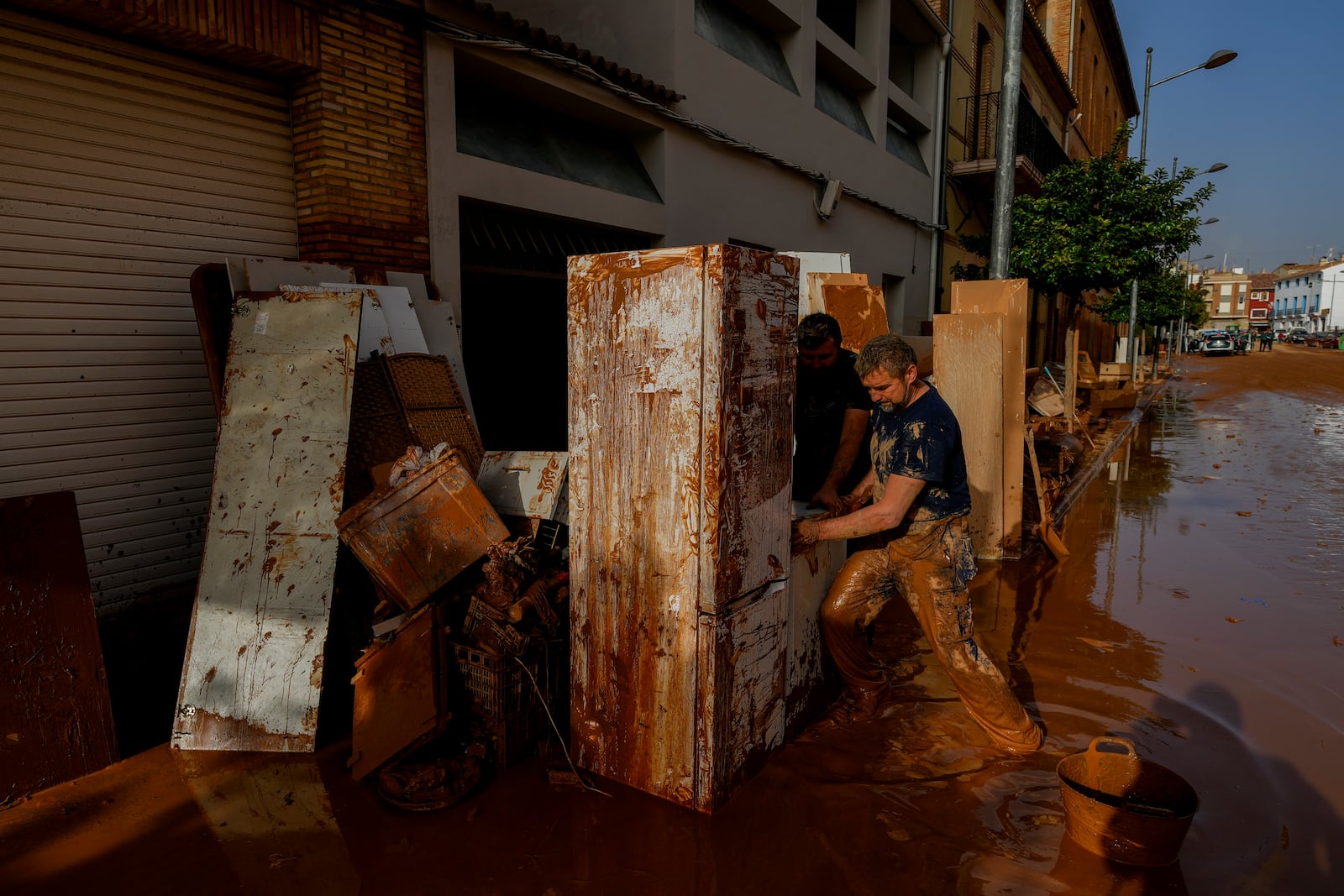 A man cleans his house hit by floods in Utiel, Spain, Wednesday, Oct. 30, 2024. (AP Photo/Manu Fernandez)