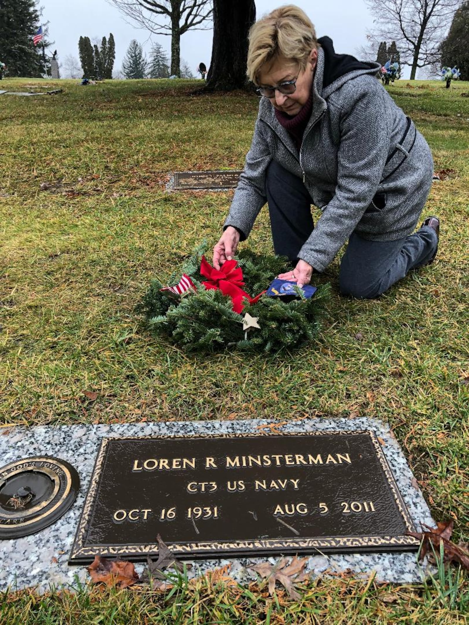 Sonya Ryhal of the Lagonda Chapter of Daughters of the American Revolution lays a wreath in honor of Korean War veteran Loren Minsterman at Rose Hill Burial Park as part of National Wreaths Across America Day on Saturday. Photo by Brett Turner