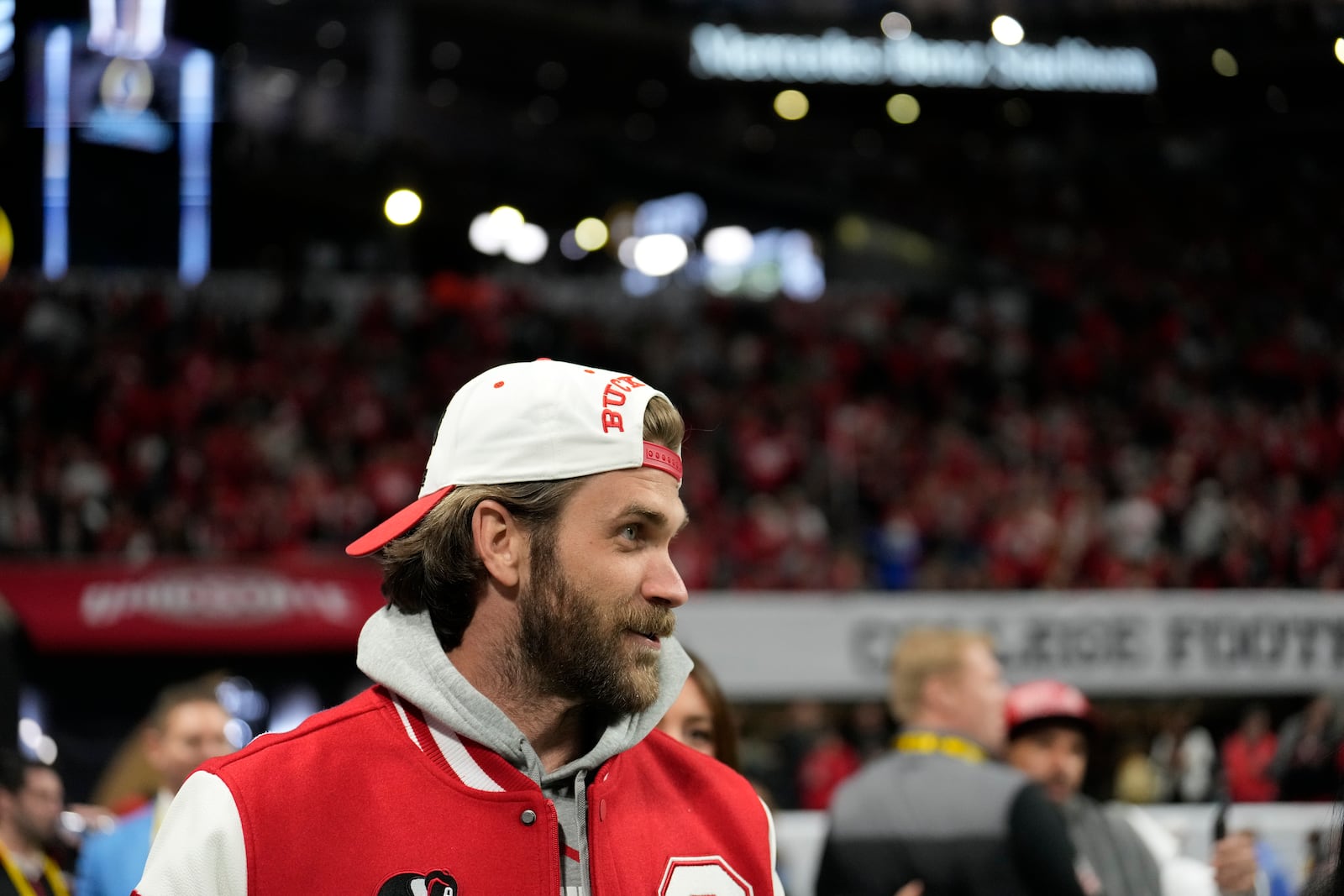 Philadelphia Phillies First Baseman Bryce Harper watches during warm ups before the College Football Playoff national championship game between Ohio State and Notre Dame Monday, Jan. 20, 2025, in Atlanta. (AP Photo/Brynn Anderson)