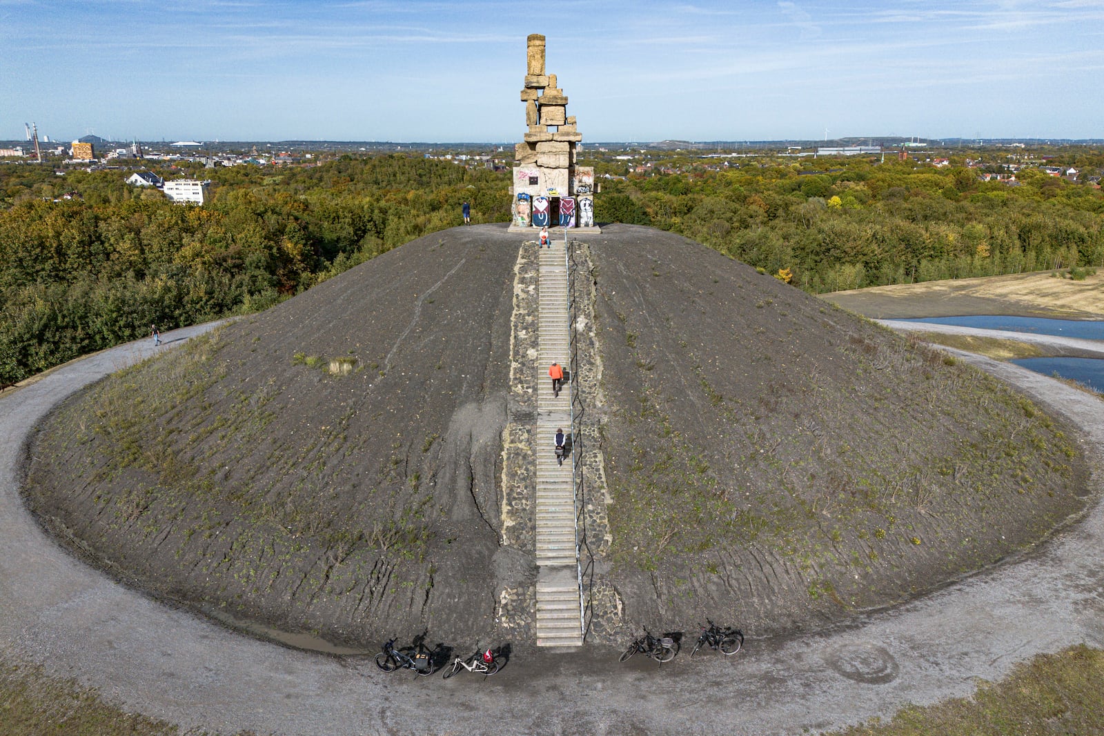 FILE - People walking up the stairs of the former mining pit Rheinelbe to the sculpture "Himmelstreppe" on a sunny warm fall Wednesday in Gelsenkirchen, Germany, Oct. 16, 2024. (AP Photo/Martin Meissner, File)