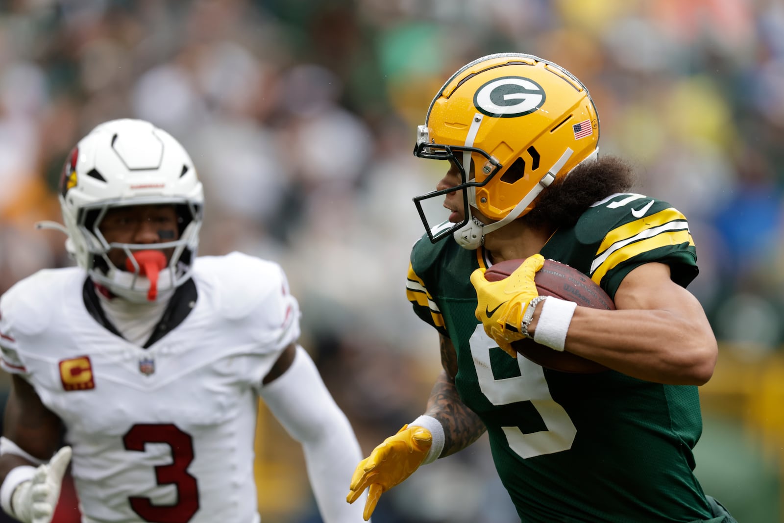 Green Bay Packers wide receiver Christian Watson (9), defended by Arizona Cardinals safety Budda Baker (3), has a 44-yard reception for a touchdown during the first half of an NFL football game, Sunday, Oct. 13, 2024, in Green Bay. (AP Photo/Matt Ludtke)