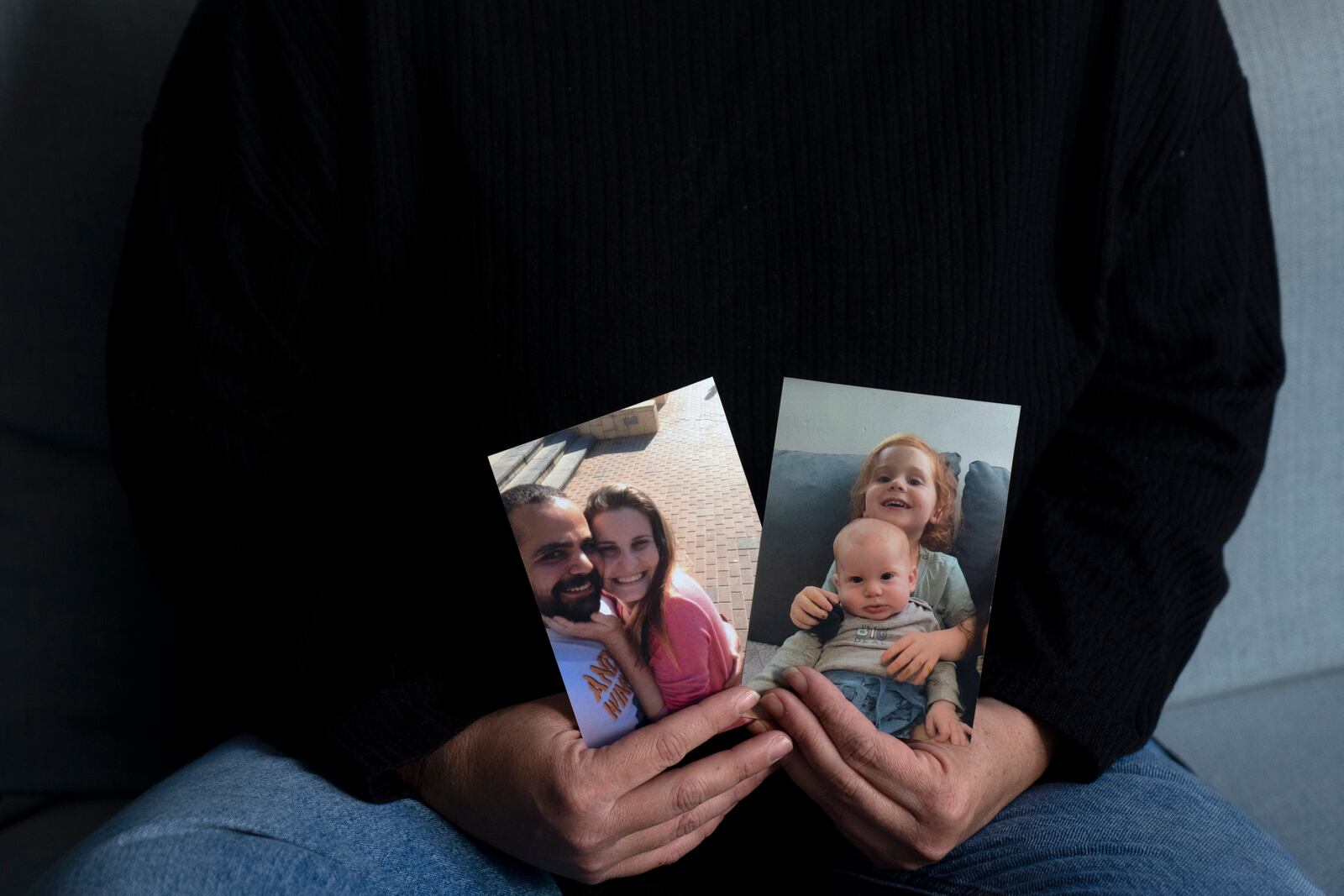 Yifat Zailer shows photos of her cousin, Shiri Bibas, center, her husband Yarden, left, and their sons Ariel, top right, and Kfir, who were taken hostage by Hamas militants, at her home in Herziliyya, Israel, Wednesday, Jan. 15, 2025. (AP Photo/Maya Alleruzzo)