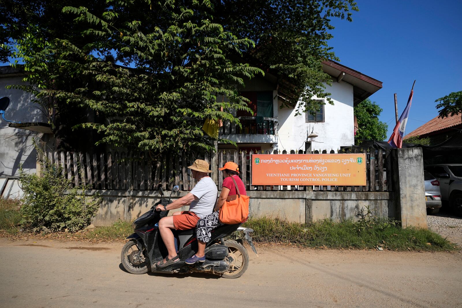 Tourists ride on a motorbike near the tourism control police station in Vang Vieng, Laos, Friday, Nov. 22, 2024. (AP Photo/Anupam Nath)