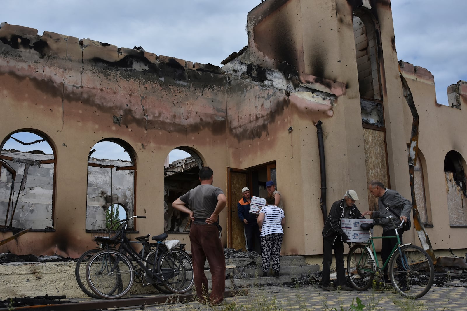 FILE - Local residents receive humanitarian aid from a volunteers in front of the Evangelical Christian Baptists prayer house in Orihiv, Ukraine, on Monday, May 22, 2023, which was destroyed the previous day by a Russian attack. (AP Photo/Andriy Andriyenko, File)